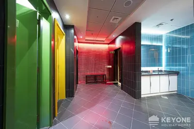 a bathroom with colorful walls and a tile floor at Modern & Stylish Studio in JVT in Dubai