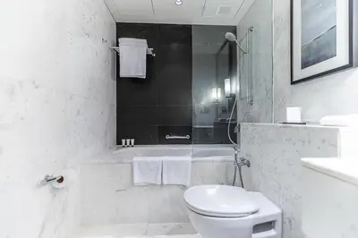 a white bathroom with a toilet and a bath tub at FAHH - Amazing Studio in Emaar Fashion Avenue in Dubai