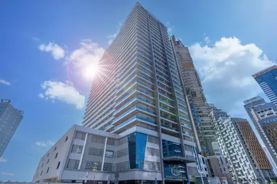 a tall building with the sun in the sky at Spacious Apartment with Balcony Near Dubai Mall in Dubai