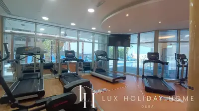 a gym with treadmills and ellipticals in a building at LUX The Sky View Suite Dubai Marina in Dubai