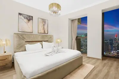 a bedroom with a large white bed with a large window at FIRST CLASS 3BR with full BURJ KHALIFA and FOUNTAIN VIEW in Dubai