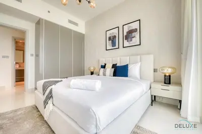 a white bedroom with a large white bed with blue pillows at Idyllic 1BR at Sunrise Bay Tower 1 Emaar Beachfront Dubai Marina by Deluxe Holiday Homes in Dubai
