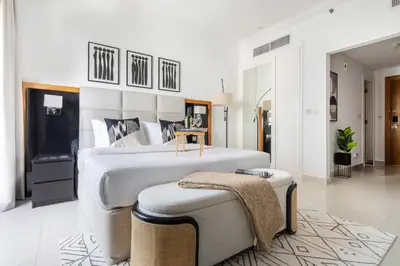 a large white bedroom with a large bed and a stool at Frank Porter - Capital Bay Tower B in Dubai