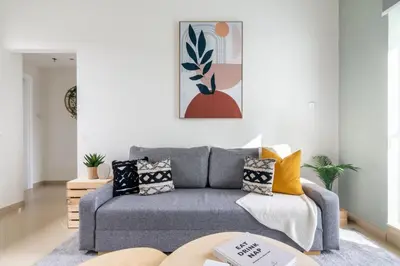 a living room with a gray couch and a painting at GuestReady - Jumeirah Skyline Apartment in Dubai