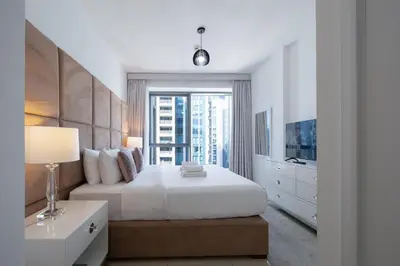 a bedroom with a white bed and a window at Signature 2BR with Burj Khalifa & Fountain View in Dubai