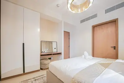 a white bedroom with a bed and a mirror at Modern 2BR High Floor Haven in Vida Dubai Marina in Dubai
