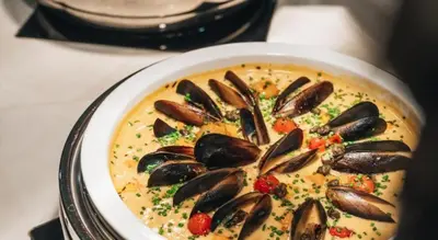 a bowl of soup with mussels on a table at DAMAC Towers by Paramount Hotels & Resorts Dubai in Dubai