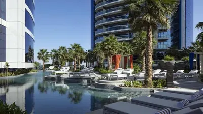 a resort pool with lounge chairs and palm trees at DAMAC Towers by Paramount Hotels & Resorts Dubai in Dubai