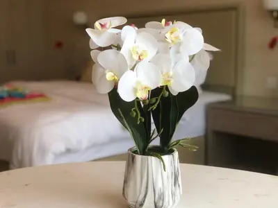 a silver vase filled with white flowers on a table at ORION in Dubai
