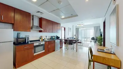 a large kitchen with wooden cabinets and a dining table at LV38 - Elegant 2BHK in Lake View Tower in Dubai