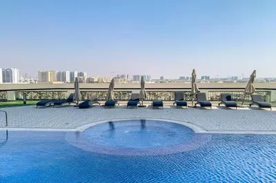 a swimming pool with chairs and umbrellas on a building at Frank Porter - Starz by Danube in Dubai