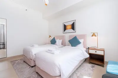 two beds in a room with white sheets and blue pillows at Vacay Lettings - High floor Burj Khalifa & Fountain view 3 bed in Dubai