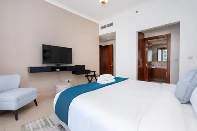 a bedroom with a bed and a tv and a chair at Vacay Lettings - High floor Burj Khalifa & Fountain view 3 bed in Dubai