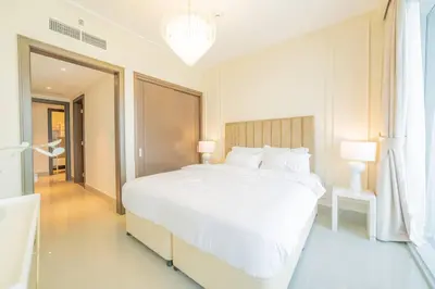 a white bedroom with a large bed and a window at Luxury 3BR with Burj Khalifa Views, Pool, Gym, and Free Parking in Dubai