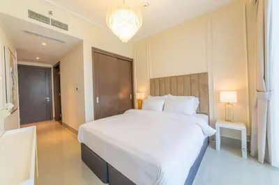 a bedroom with a large white bed and a chandelier at Luxury 3BR with Burj Khalifa Views, Pool, Gym, and Free Parking in Dubai