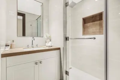 a white bathroom with a shower and a sink at Luxury 3BR with Burj Khalifa Views, Pool, Gym, and Free Parking in Dubai