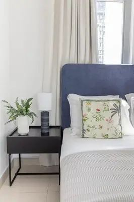 a bed with a blue headboard and a table with a pillow at Frank Porter - Marina Wharf 2 in Dubai