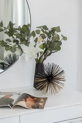 a vase with flowers on a table next to a book at Frank Porter - Marina Wharf 2 in Dubai