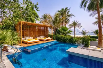 a swimming pool with a villa in the background at FIVE Palm Beachfront Villa -Private Pool & Jacuzzi, Panoramic Views, by Exclusive Holiday Homes in Dubai