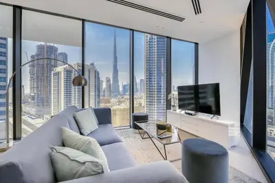 a living room with a large couch and a tv at Maison Privee - Luxury Apt with Burj Khalifa Vw & Dubai Canal Access in Dubai