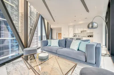 a living room with a blue couch and a kitchen at Maison Privee - Luxury Apt with Burj Khalifa Vw & Dubai Canal Access in Dubai
