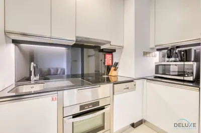 a kitchen with white cabinets and stainless steel appliances at Steps Away From Marina Mall with Iconic Marina Canal Views, The Address Residences, Dubai Marina by Deluxe Holiday Homes in Dubai