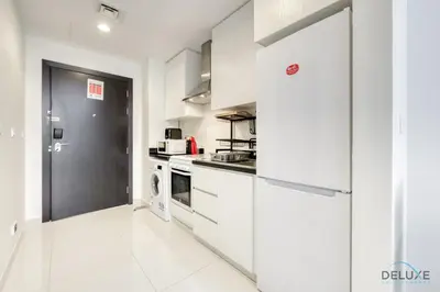 a kitchen with white cabinets and a black door at Superb Studio at Damac Celestia A Dubai South By Deluxe Holiday Homes in Dubai