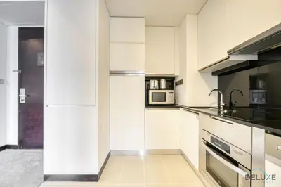 a kitchen with white cabinets and a microwave at Upscale Studio at The Address Residences Dubai Marina by Deluxe Holiday Homes in Dubai