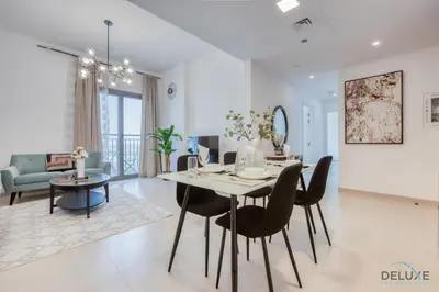 a dining room and living room with a table and chairs at Fancy 2BR at Hayat Boulevard 2A Town Square By Deluxe Holiday Home in Dubai