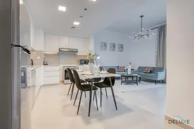 a kitchen and living room with a table and chairs at Fancy 2BR at Hayat Boulevard 2A Town Square By Deluxe Holiday Home in Dubai