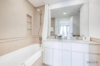 a bathroom with two sinks and a tub and a mirror at Fancy 2BR at Hayat Boulevard 2A Town Square By Deluxe Holiday Home in Dubai