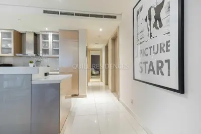 a white kitchen with a picture on the wall at Quill Residence at Paramount Towers 3 BR Creek View in Dubai