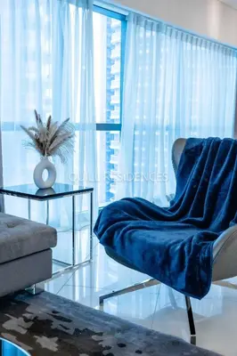 a living room with a blue chair and a table at Quill Residence at Paramount Towers 3 BR Creek View in Dubai