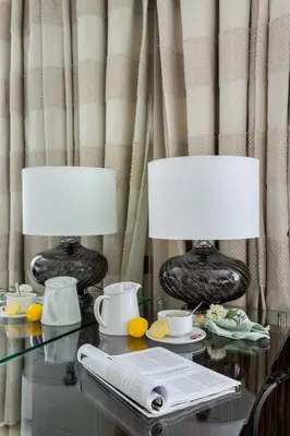 two lamps on a glass table with a plate of food at Frank Porter - Bonnington in Dubai