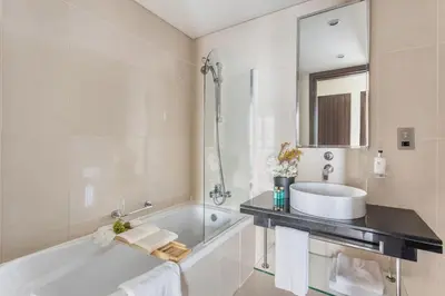 a bathroom with a tub and a sink and a mirror at Frank Porter - Bonnington in Dubai