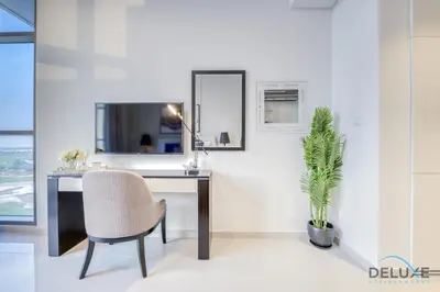 a desk with a chair and a plant in a room at Sunlit Studio at Golf Promenade 2A DAMAC Hills By Deluxe Holiday Homes in Dubai