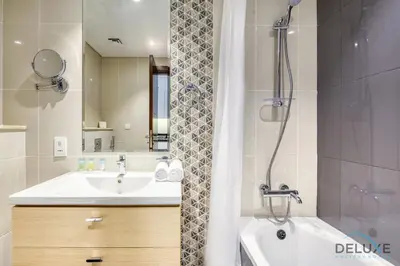 a bathroom with a tub and a sink and a shower at Sunlit Studio at Golf Promenade 2A DAMAC Hills By Deluxe Holiday Homes in Dubai