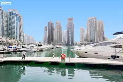a man walking on a dock next to a marina with boats at Designer apartment on the Marina Walk in Dubai