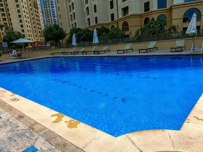 a large blue swimming pool with benches and umbrellas at Marco Polo - Experience beachfront luxury at Bahar 6 JBR in Dubai
