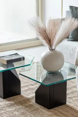a glass coffee table with a vase with feathers on it at Frank Porter - Al Samar in Dubai