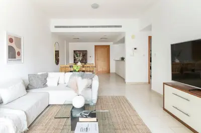 a living room with a white couch and a tv at Frank Porter - Al Samar in Dubai
