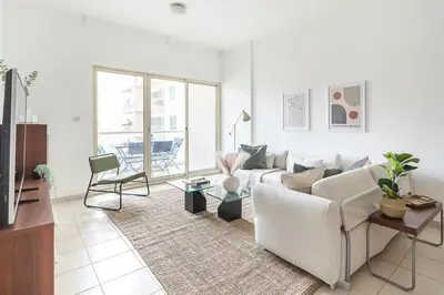 a white living room with a couch and a table at Frank Porter - Al Samar in Dubai