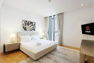 a bedroom with a white bed and a tv at Livbnb - Tranquil 2BR in Bluewaters in Dubai