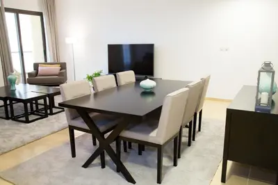 a dining room table with chairs and a television at HiGuests - Charming Apt in JBR with Balcony by the Beach in Dubai