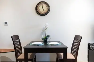 a table with two chairs and a clock on the wall at White Sage - Elite Residence Studio in Dubai