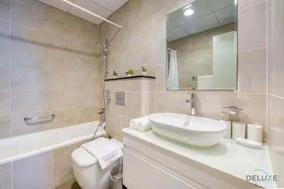 a bathroom with a sink and a toilet and a mirror at Prime 1BR at Carson B DAMAC Hills Dubailand by Deluxe Holiday Homes in Dubai