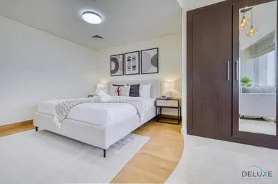 a white bedroom with a bed and a sliding door at Calm Studio at Sky Gardens DIFC by Deluxe Holiday Homes in Dubai