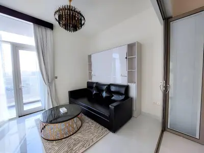 a living room with a black couch and a glass table at Spacious, Economical Apt Near Miralcz Garden in Dubai