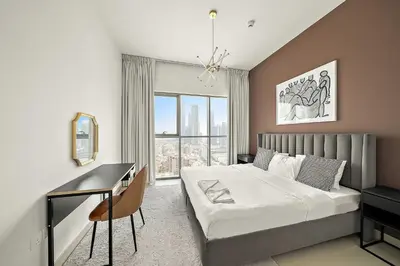 a bedroom with a bed and a desk and a window at Silkhaus Burj Khalifa view large 2BDR in great location in Dubai