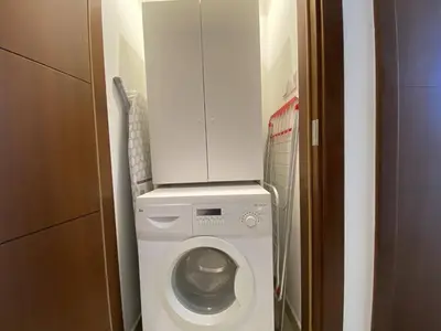a washing machine in a small bathroom with a cabinet at Lux BnB Standpoint Tower Burj & Fountain Views in Dubai